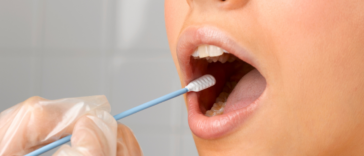 A woman getting a cotton swab inserted into her mouth.