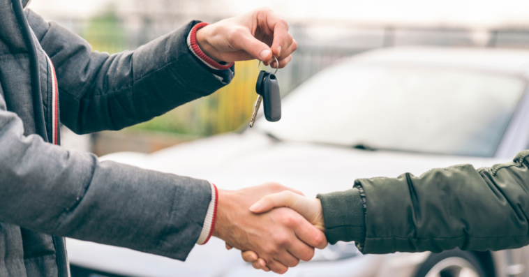 people shaking hands and exchanging car keys