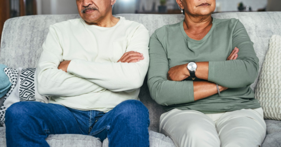 upset older couple seated on couch