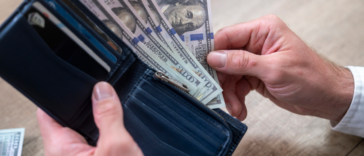 person holding wallet full of cash