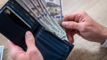 person holding wallet full of cash