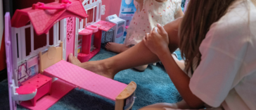 preteen girl playing dolls with toddler