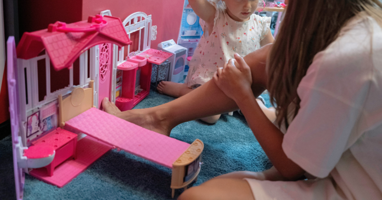 preteen girl playing dolls with toddler