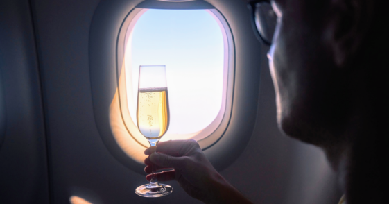silhouette of person holding champagne by airplane window