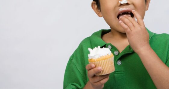 Young boy eating a cupcake.