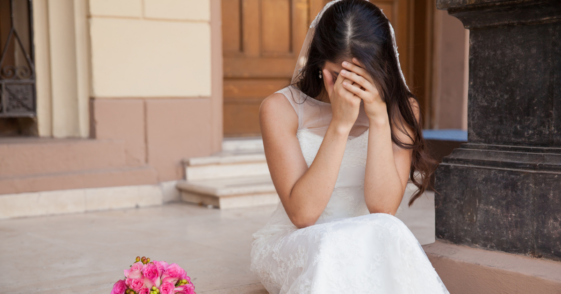 A bride crying on stairs.