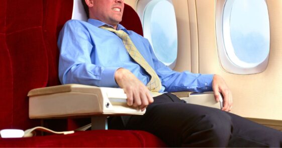Man has a fear of flying. He sits grasping the chair.