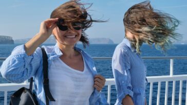 Two women enjoying sea travel on cruise ship, hair flying in the wind.