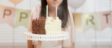 Medium shot of a young girl blowing out candles, celebrating her birthday at home.