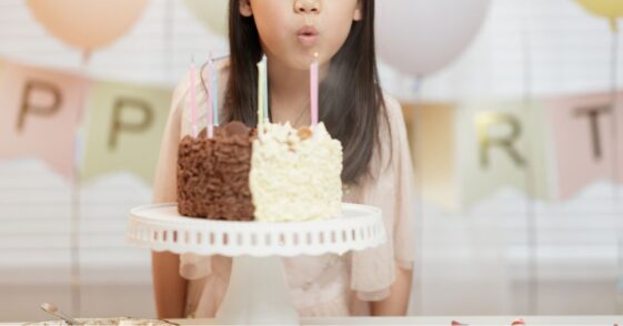 Medium shot of a young girl blowing out candles, celebrating her birthday at home.