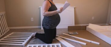 A pregnant woman building a baby crib.