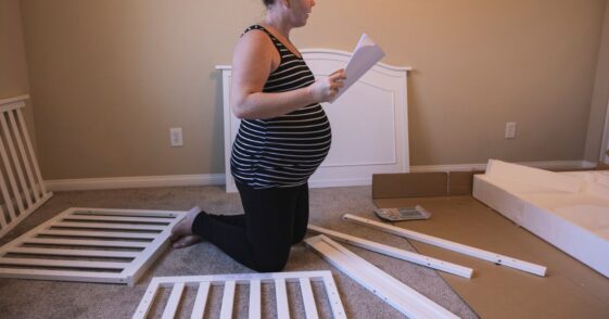 A pregnant woman building a baby crib.