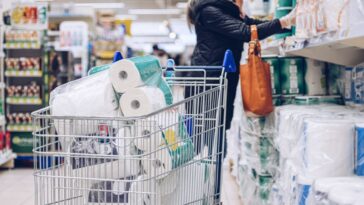 Woman shopping at supermarket choosing toilet paper.