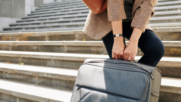 A woman hauling a heavy suitcase up a staircase.