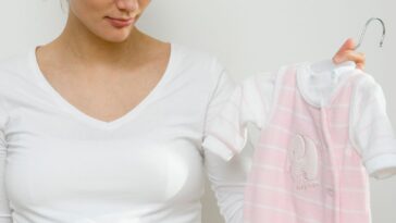 Pregnant woman holding up a onesie