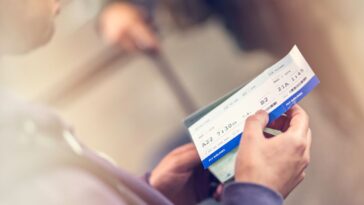 Close up of a man holing airplane ticket, blurred background.