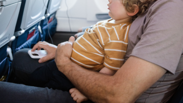 father and child seated together on airplane