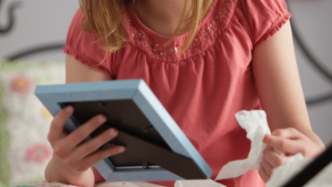 Little girl looking at a picture in a frame and holding tissues.