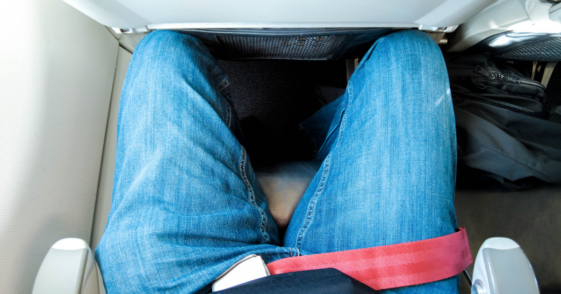 Tall man cramped in airplane seating