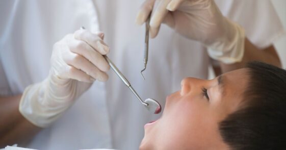 Boy with mouth open being examined by dentist.