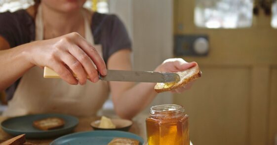 Woman spreading freshly extracted honey on bread.