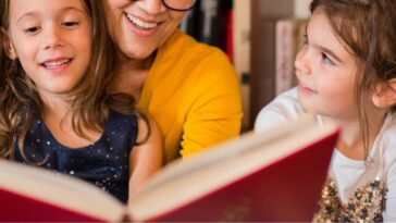 Happy older woman reading tales for her two beautiful granddaughters.