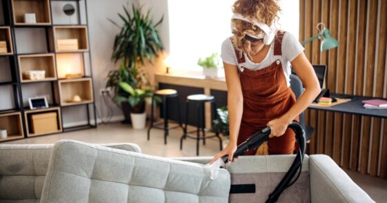 Cleaner doing deep washing of a sofa with professional equipment.