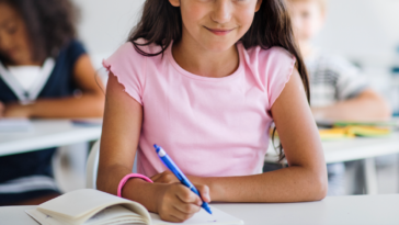 A young girl at her desk in school.
