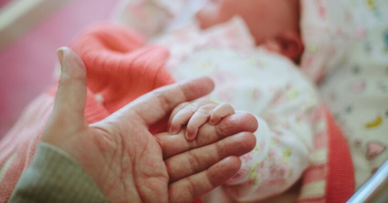 Newborn baby holding onto mother's hand