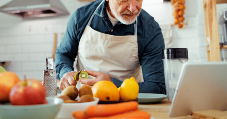 older man cooking while following a recipe on a tablet