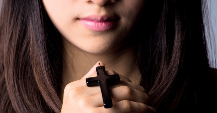 teen holds cross pendant in hand