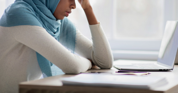 woman in hijab looking at laptop with concern