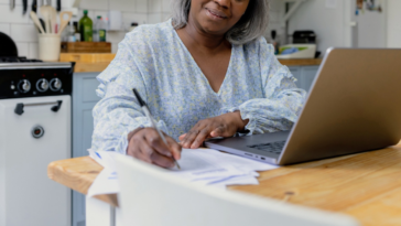 older woman seated at kitchen table taking notes