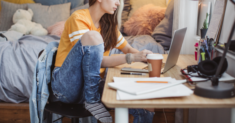 A girl sitting at her desk in a dorm room.