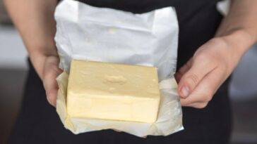 A hand holds butter in a pack close-up.