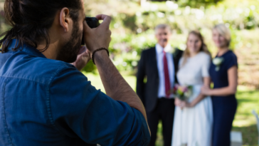 A photographer taking a picture of a bride and her parents.