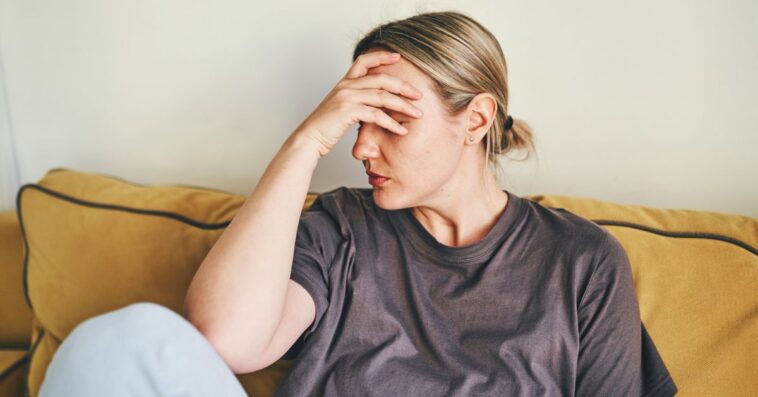 Woman resting forehead on her hand in frustration