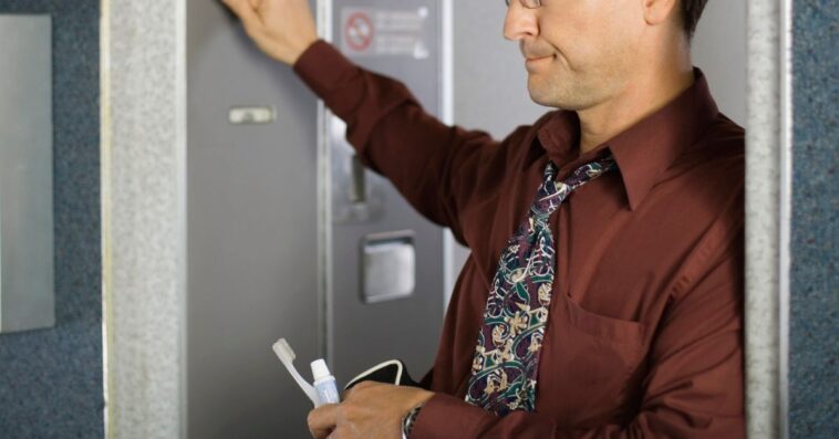 Man knocking on airplane bathroom door