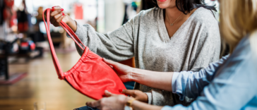 two women looking at a red bag