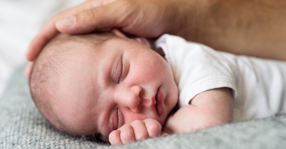 man's hand resting on baby's head