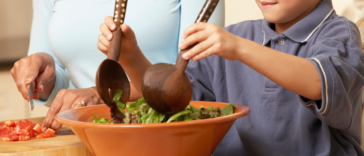 Child preparing and eating a lot of salad