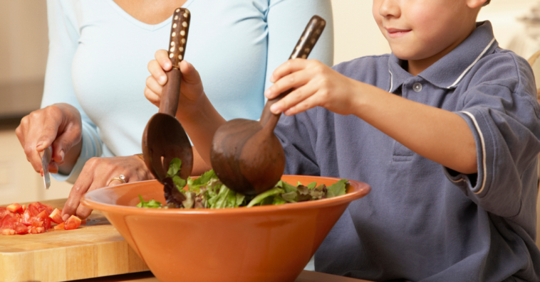 Child preparing and eating a lot of salad