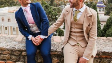 Elegant gay couple holding hands at an observation point above the city, Malaga, Spain.