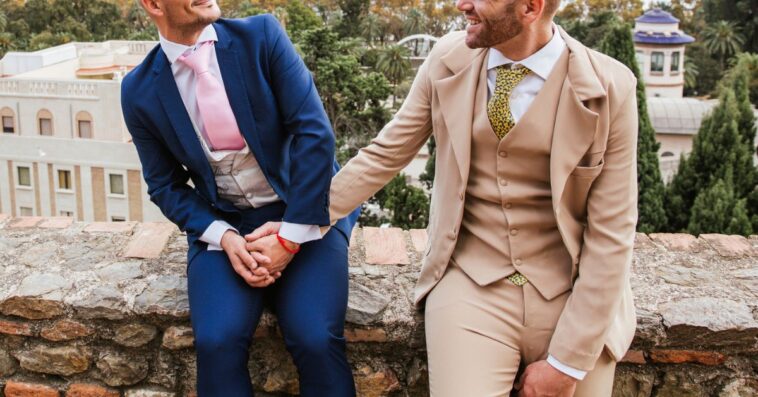 Elegant gay couple holding hands at an observation point above the city, Malaga, Spain.