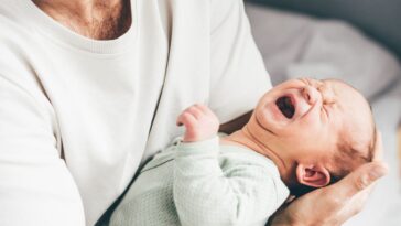 A man holds a crying baby.