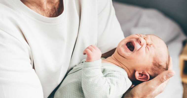 A man holds a crying baby.