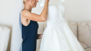 A bride wearing a veil and holding a wedding dress.
