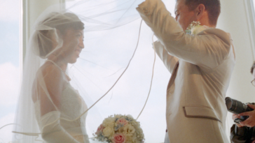 A groom pulling off the veil of a bride.