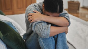 Sad depressed adolescent teen girl crying at home, worried teenager hugging knees suffering from depression.