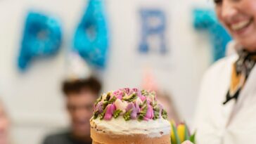 A close-up of an unrecognizable person giving a birthday cake to an unrecognizable woman for her birthday.